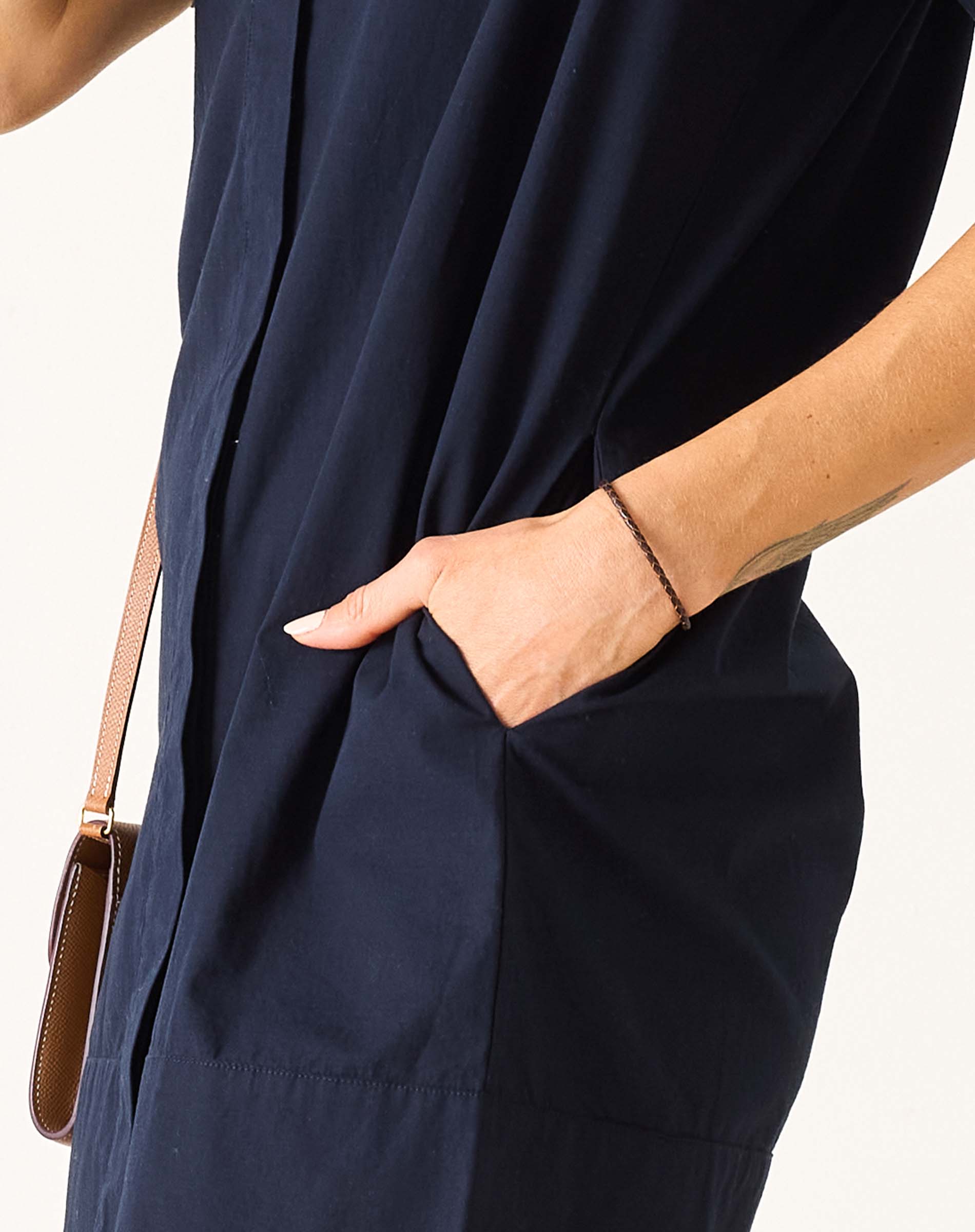 Model wearing a navy blue wide-hem dress with a side pocket.