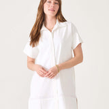 Model in a white short-sleeved sailor dress with a wide hem and button front.