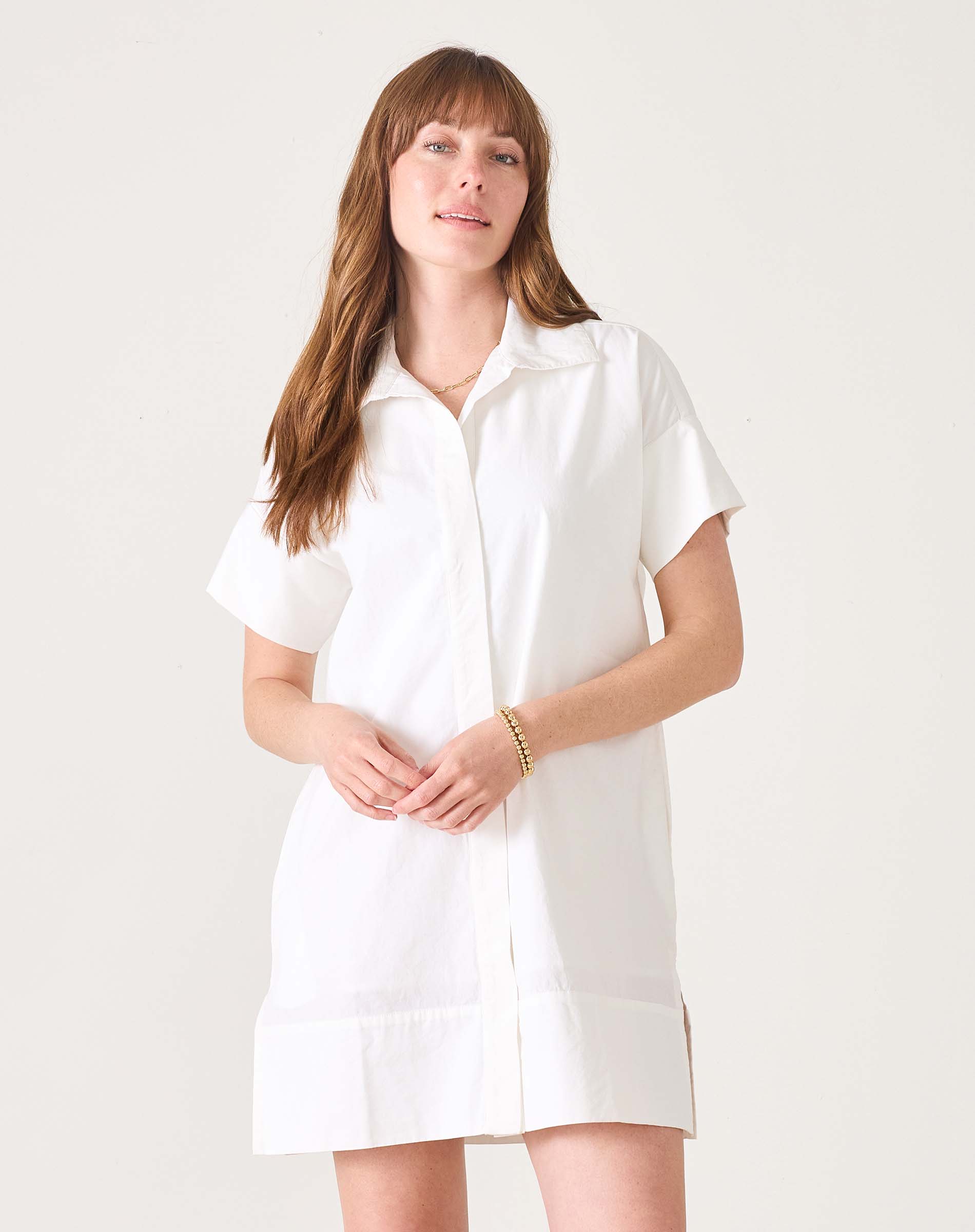 Model in a white short-sleeved sailor dress with a wide hem and button front.