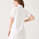 Woman in white short-sleeved sailor dress with a wide hem and button details on the sleeves.
