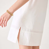 Model wearing a white sailor wide hem dress with a side slit and gold bracelet.