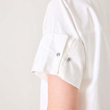 Detail of the white sailor-style wide hem dress featuring a rolled sleeve with button details.