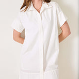 Model in a white, short-sleeved button-down shirt dress with a sailor collar and wide hem.