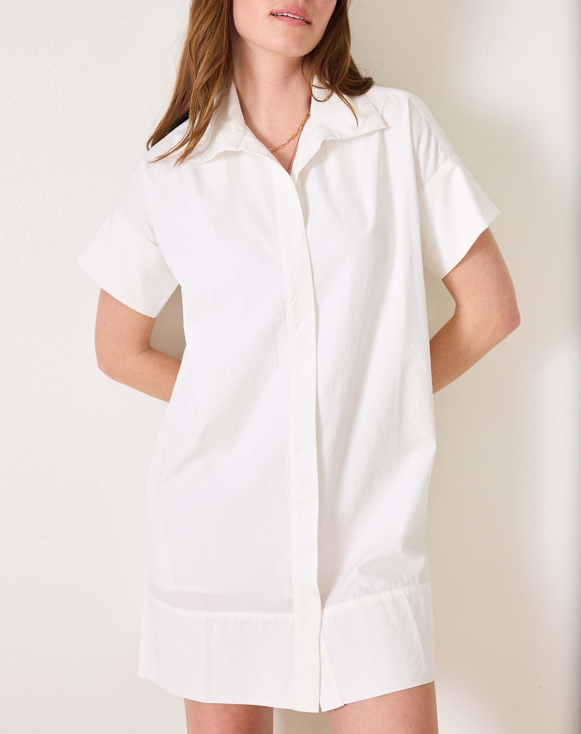 Model in a white, short-sleeved button-down shirt dress with a sailor collar and wide hem.