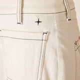 Close-up of beige pants with a brand logo on the pocket.