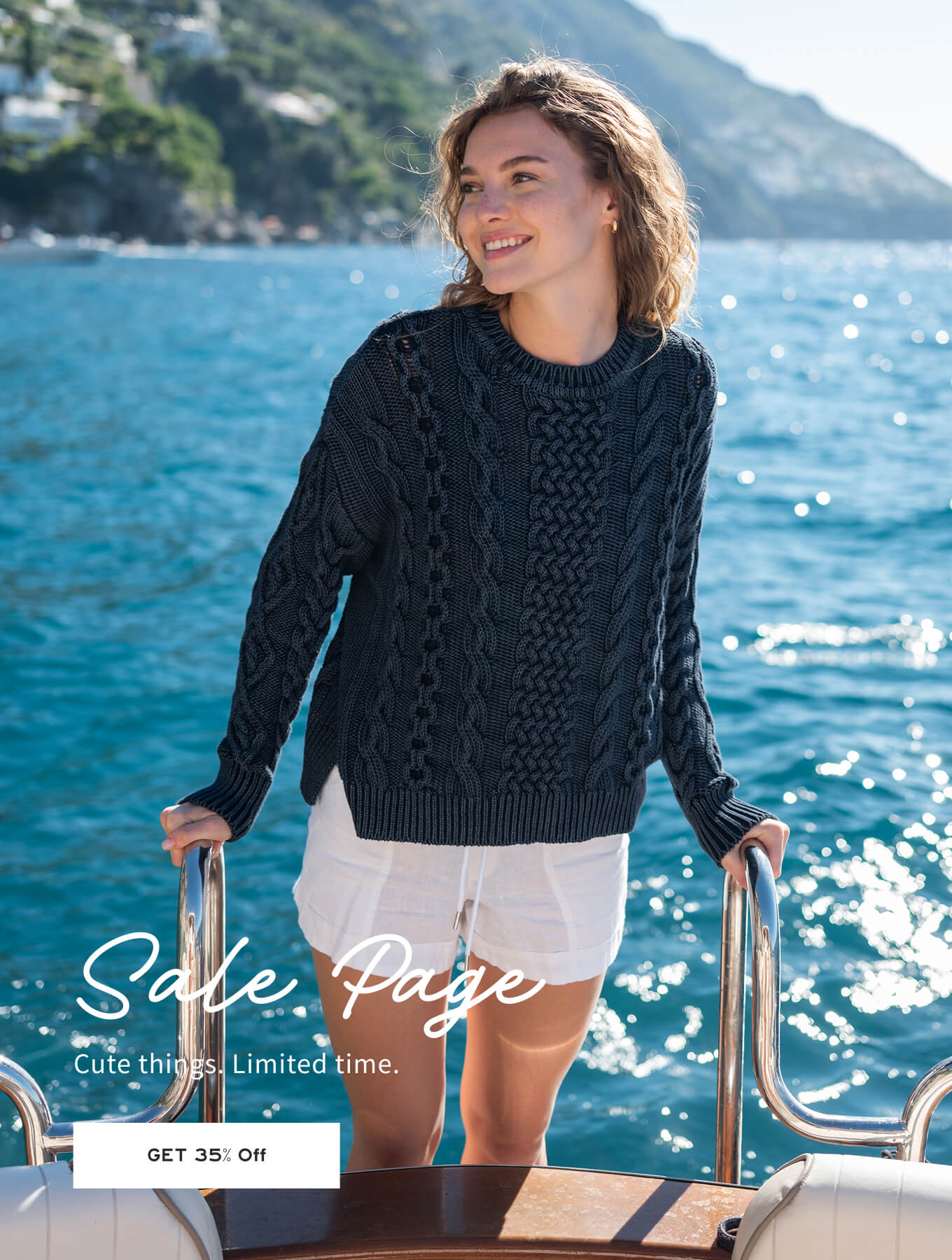 Woman in a black sweater and white shorts standing on a boat with a scenic background