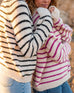 two women wearing mersea salt and sea turtlenecks in buttercream and stripes standing together in front of rocks