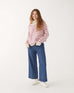 woman wearing mersea salt and sea turtleneck in buttercream and magenta stripe standing against white background