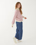 smiling woman wearing mersea salt and sea turtleneck in buttercream and magenta stripe walking against white background
