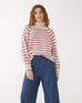 woman wearing mersea salt and sea turtleneck in buttercream and magenta stripe standing against white background