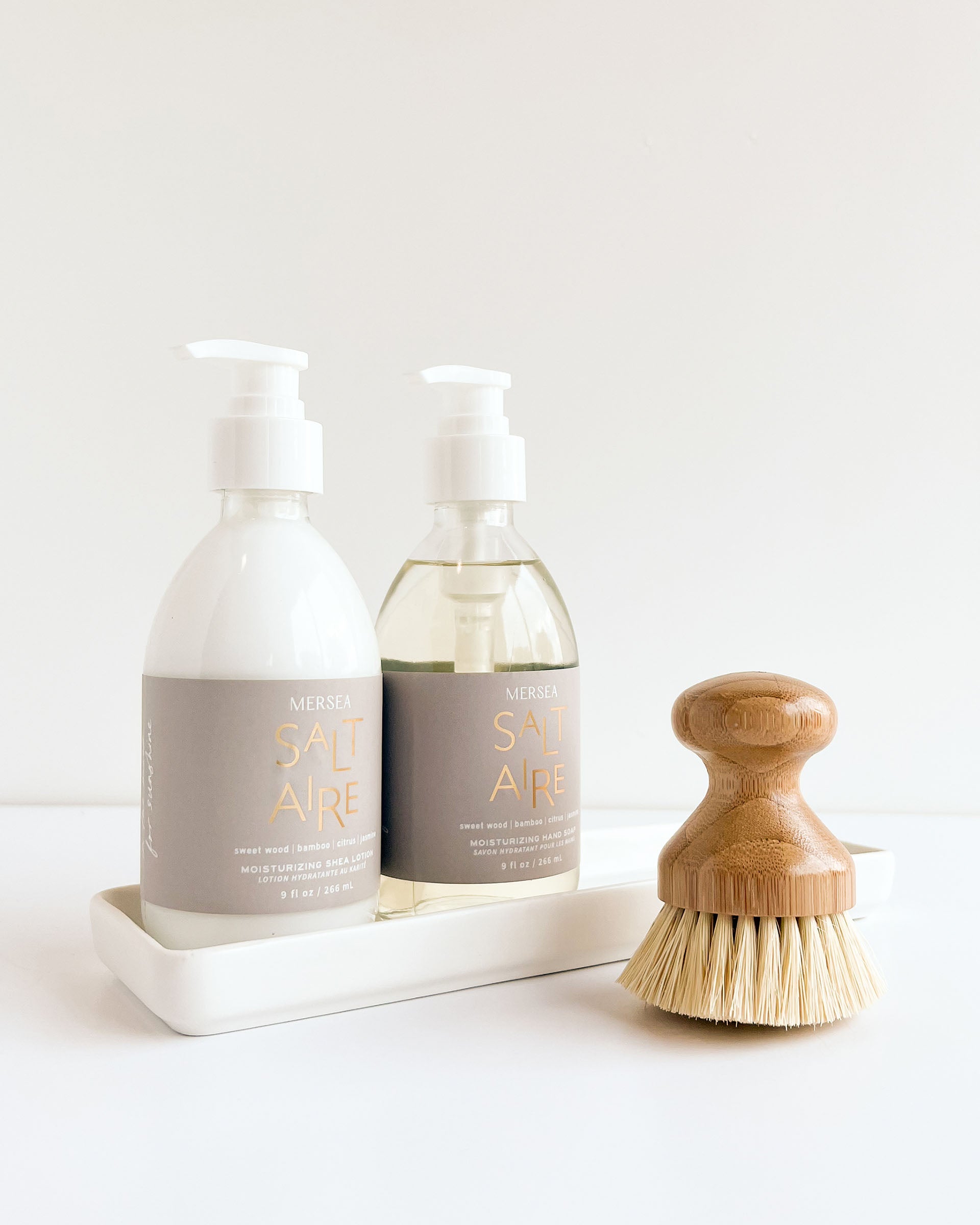 saltaire hand soap shea lotion and brush laying on a white background with tray