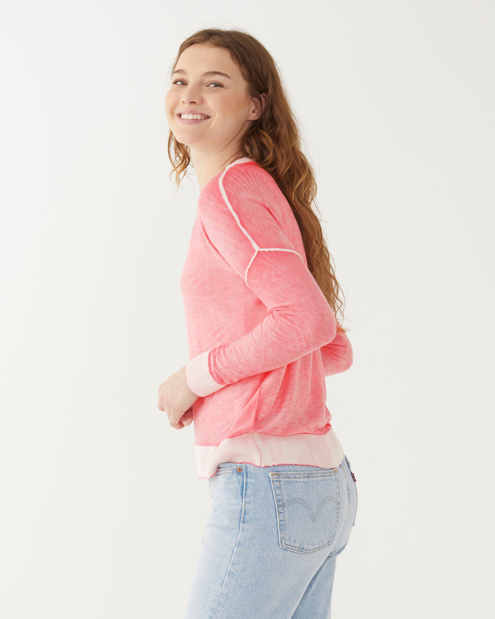 female wearing pink hand-dyed cashmere sweater sideways on a white background
