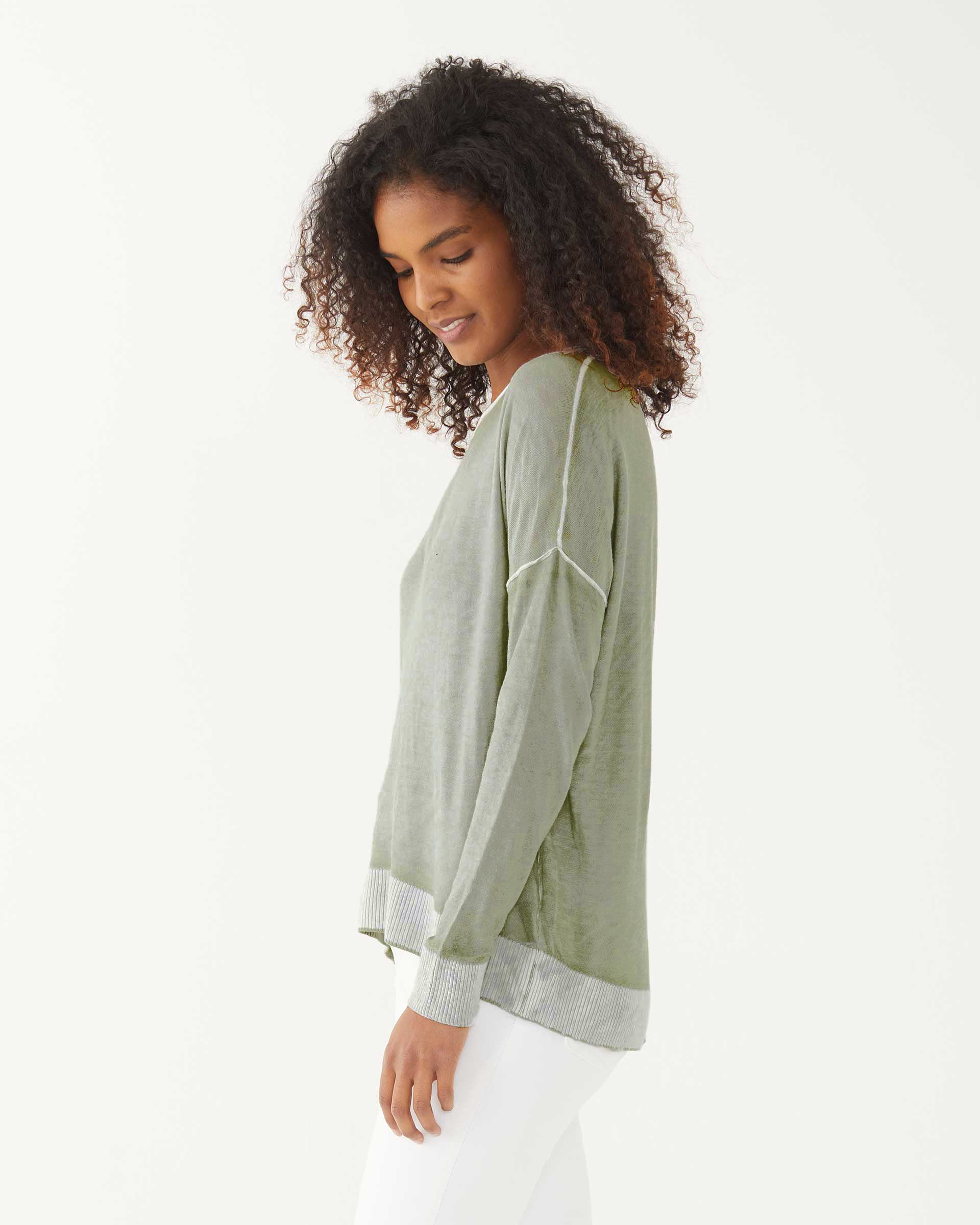 female wearing sea moss green hand-dyed cashmere sweater sideways on a white background