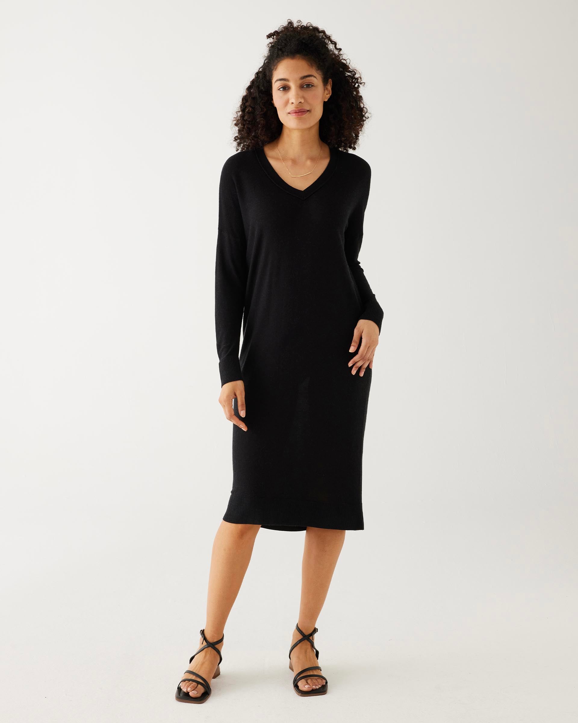 woman showcasing mersea black long sleeve v neck saltwash sweater dress with black sandals