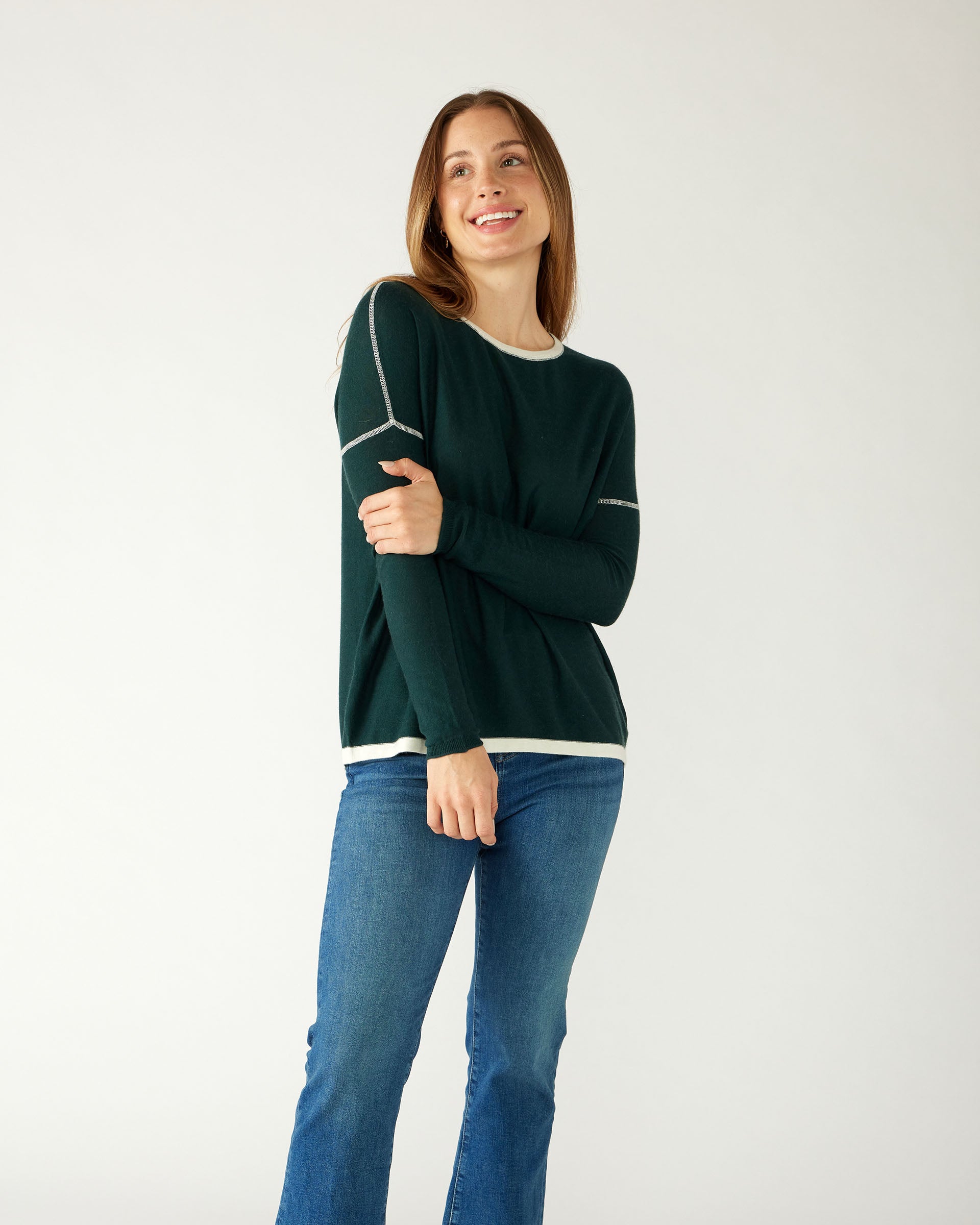 woman holding arm wearing mersea saltwash sweater in forest green