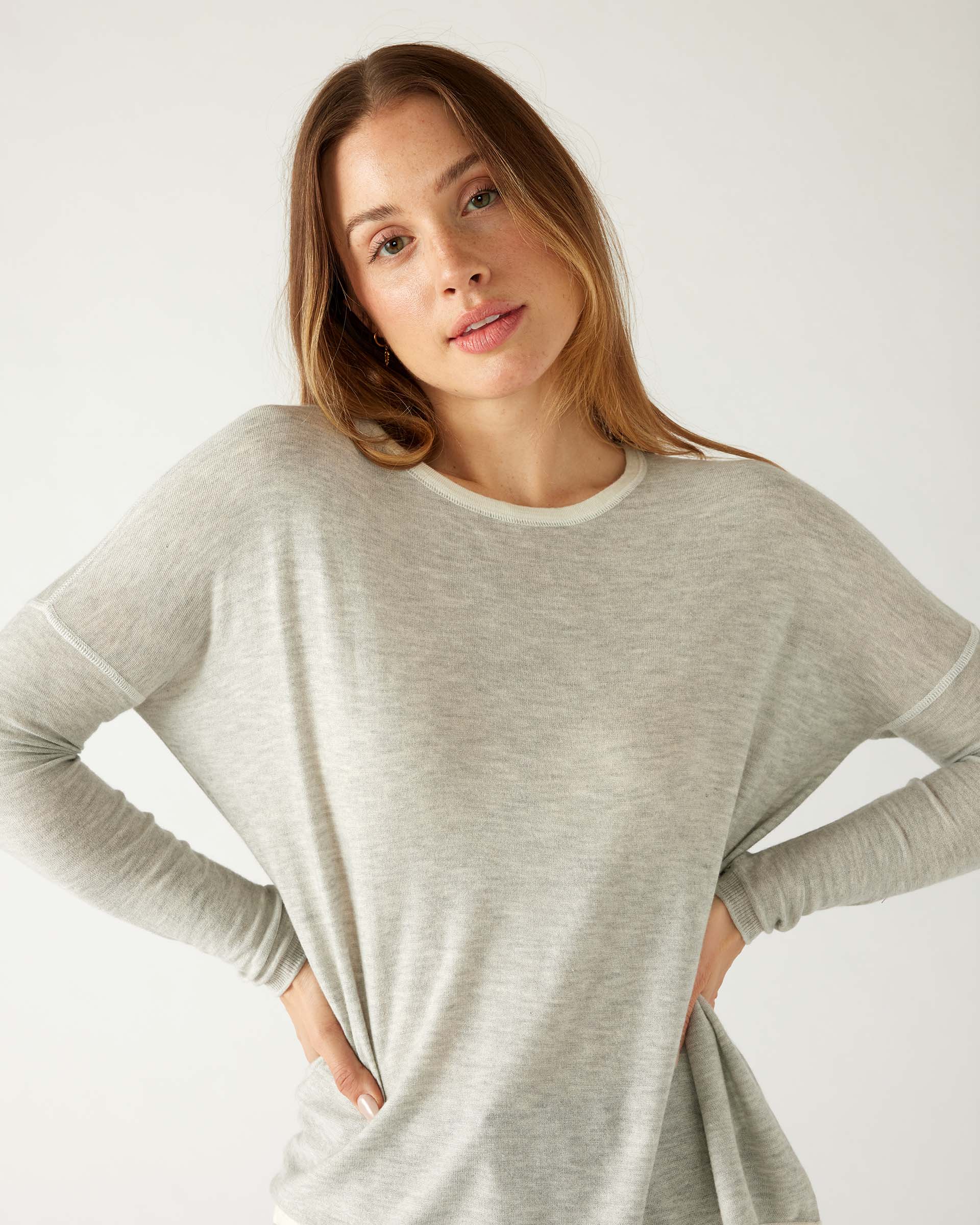 woman wearing mersea saltwash sweater in grey with arms on hips 