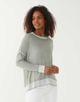 female wearing green hand dyed sweater with white jeans on a white background