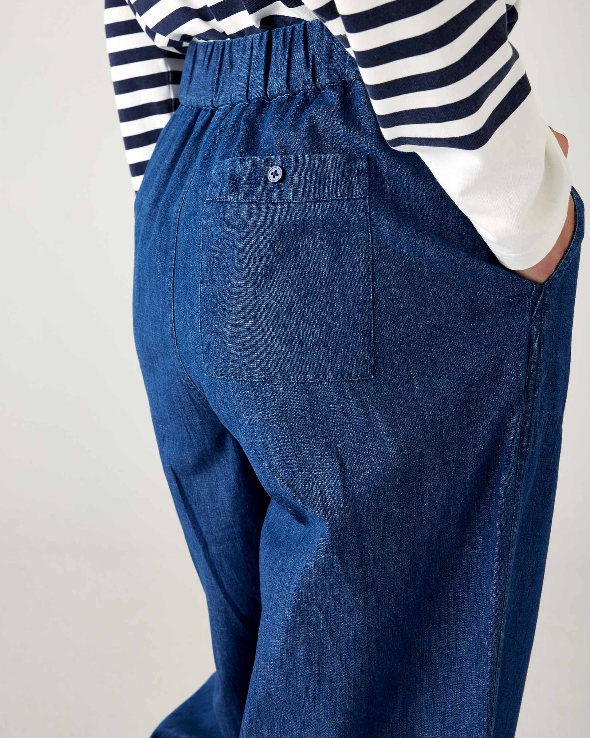 closeup of rear on woman wearing blue and white striped shirt with mersea sammie chambray pants on a white background