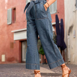 Person wearing blue denim wide-leg pants and brown sandals on a street.