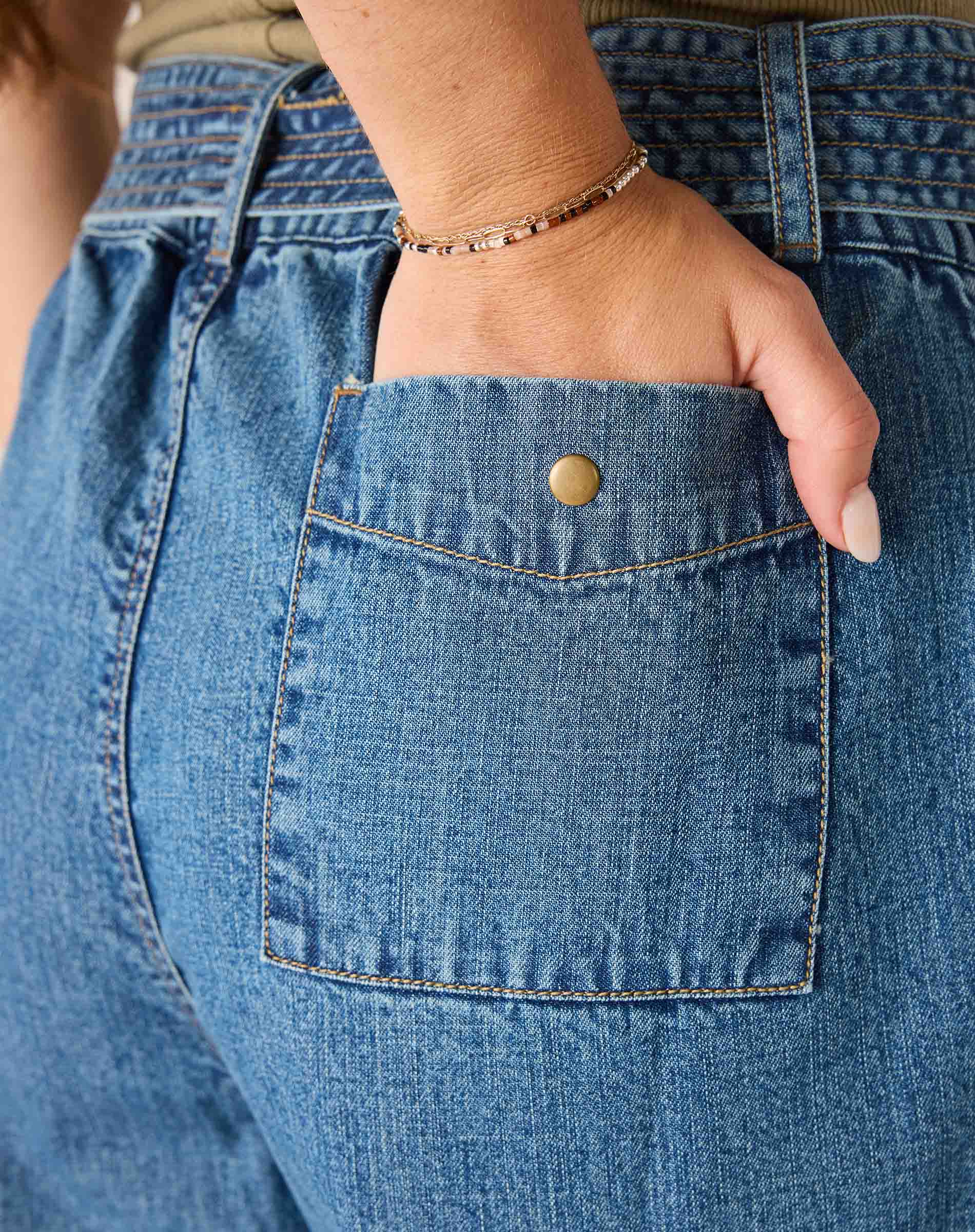 Close-up of a hand reaching into a pocket of blue jeans.
