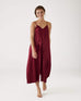 female wearing Mersea garnet satin jumpsuit standing against white background