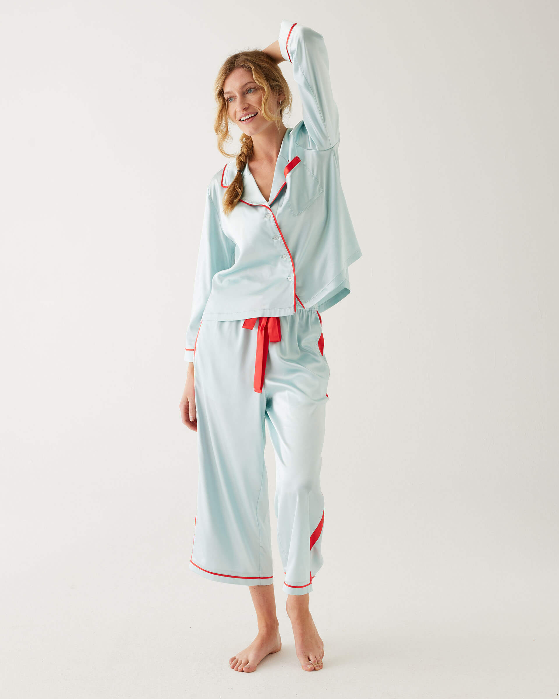 female wearing Mersea aquamarine satin sailor pajama set standing with white background