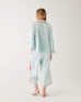 backside of female wearing Mersea aquamarine satin sailor pajama set standing with white background