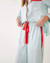 closeup of waste ties on female wearing Mersea aquamarine satin sailor pajama set standing with white background