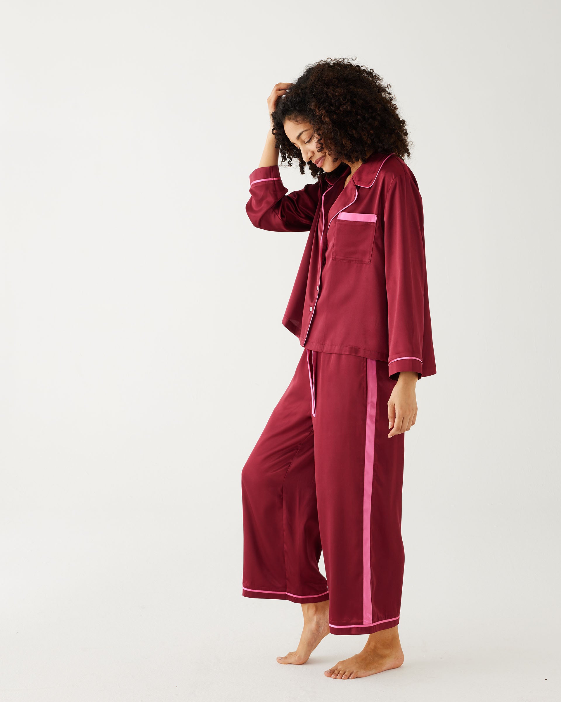 female wearing Mersea garnet satin sailor pajama set standing sideways against white background