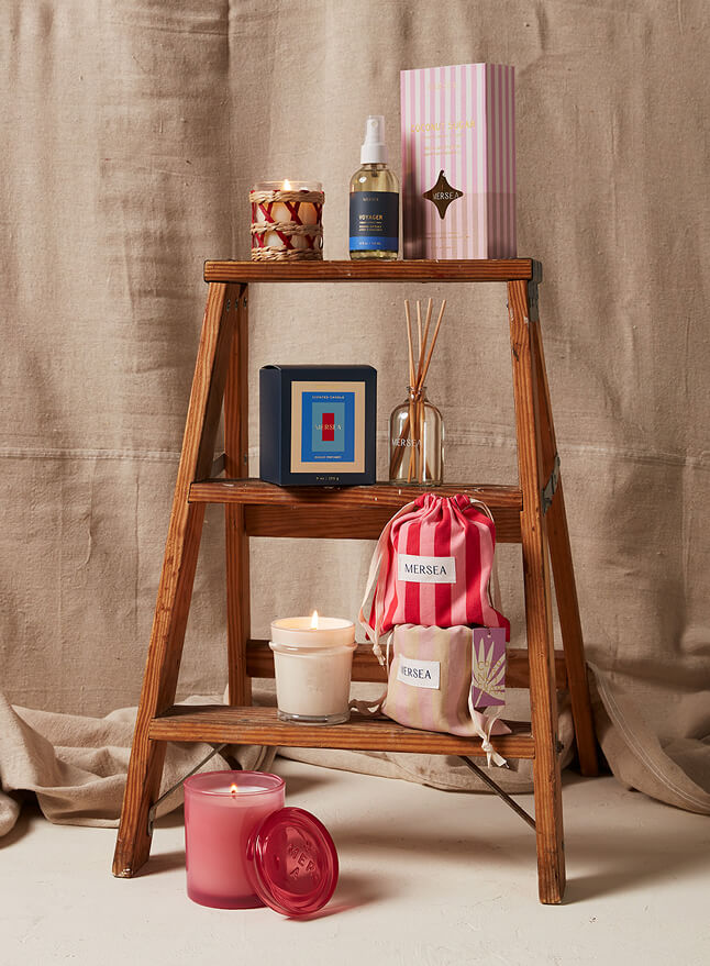 Wooden ladder with candles, bottles, and a bag on a beige background
