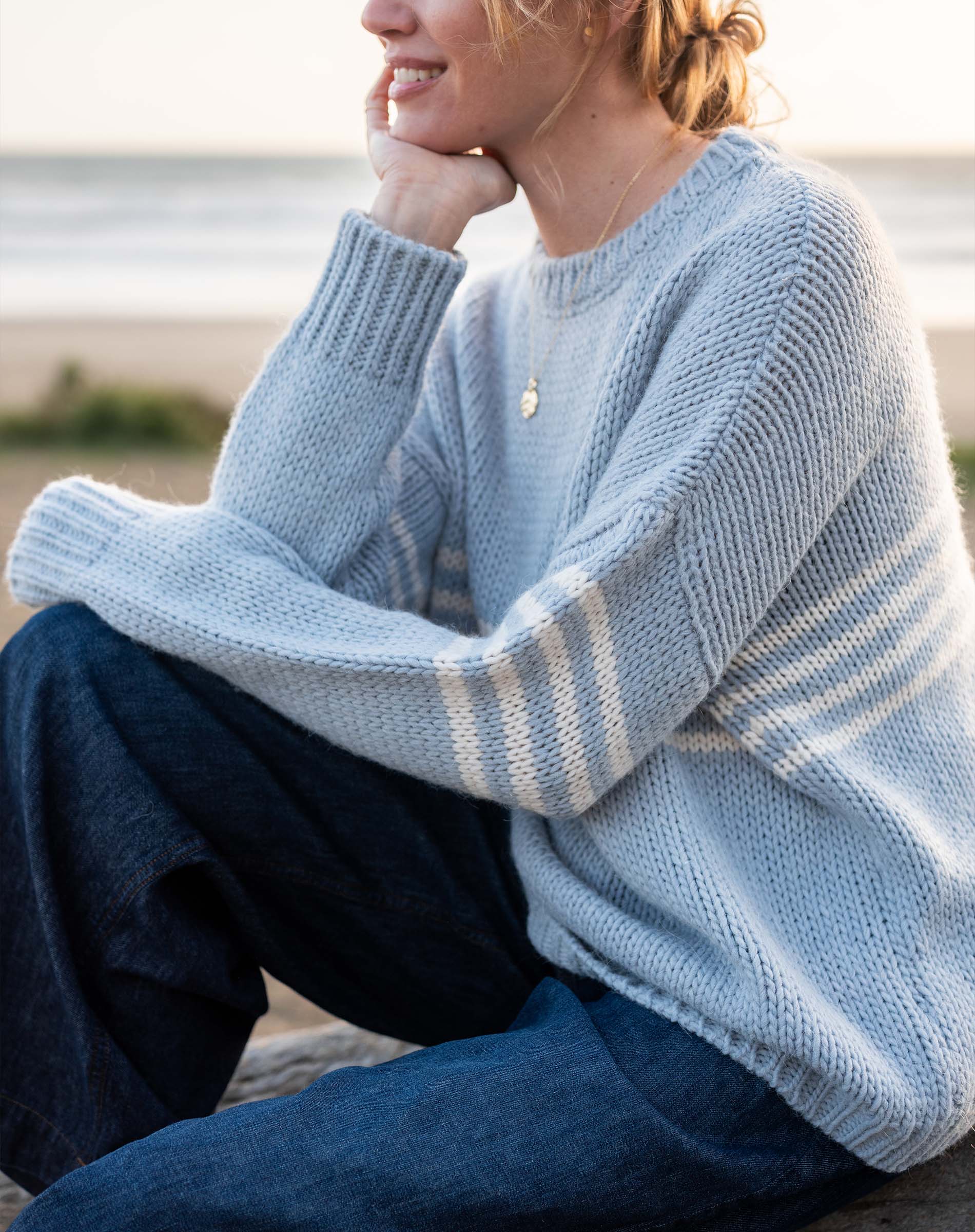 Soft sky white knit sweater with textured ribbed details and wide horizontal stripes.