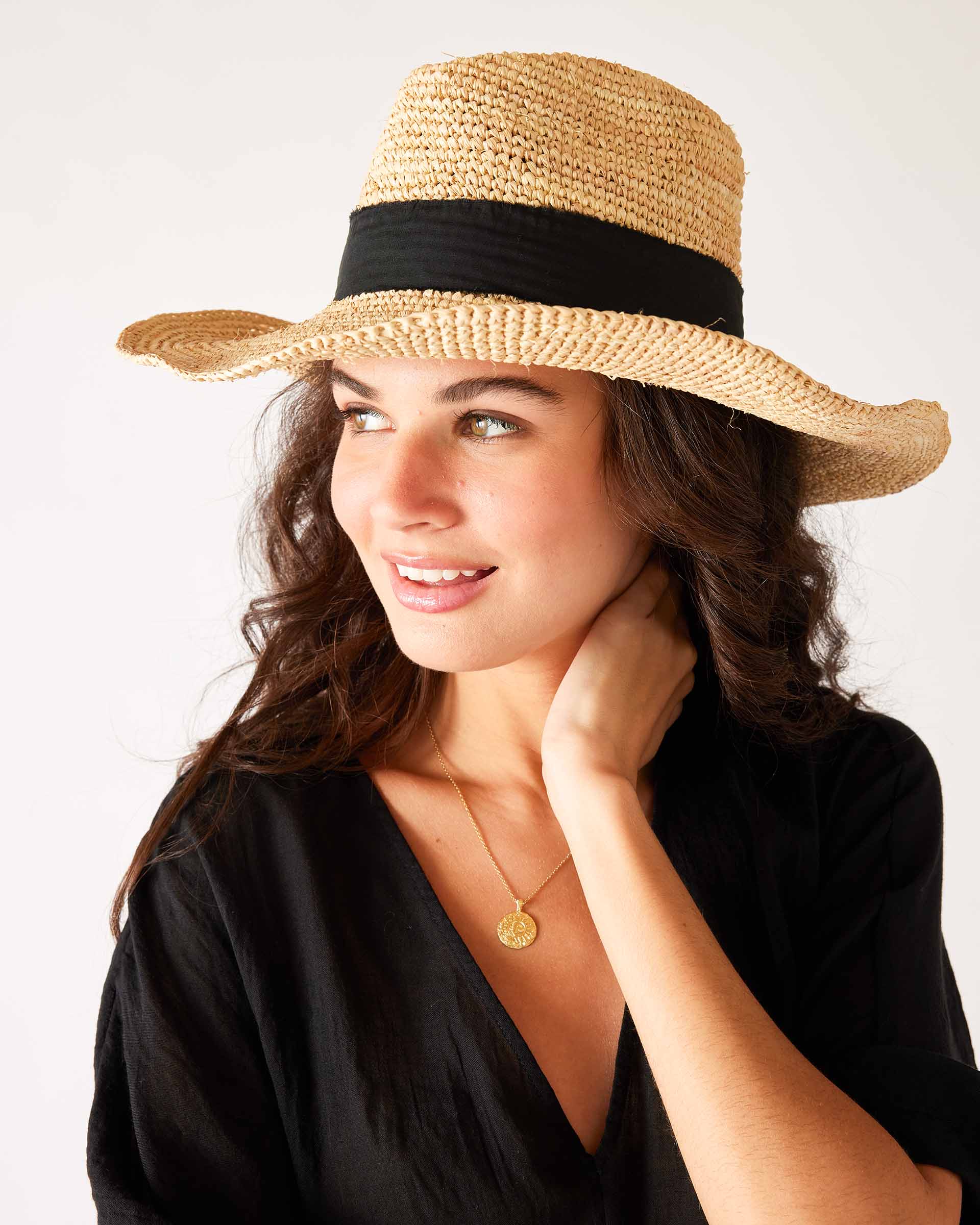 woman looking sideways in a black dress with seagrove straw hat on