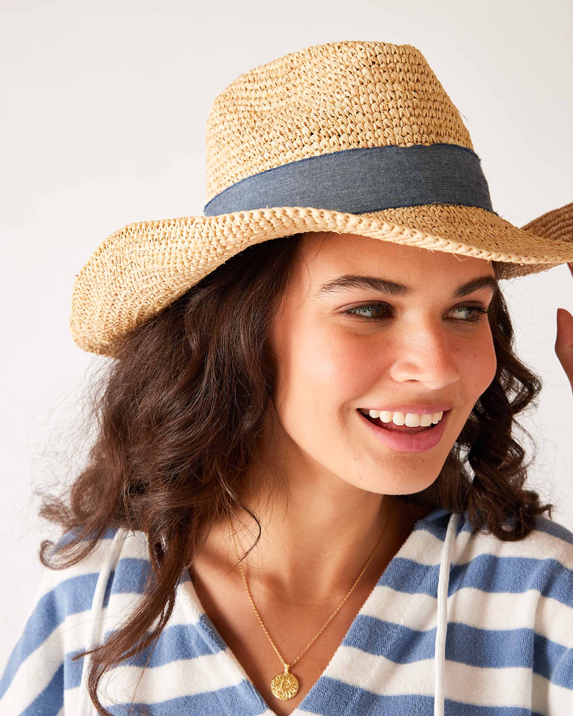 woman looking sideways wearing seagrove straw hat laughing