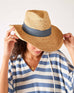 woman looking down wearing seagrove straw hat with hands on the brim