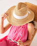top down shot of woman wearing seagrove straw hat with hand on the brim and sunglasses in hand
