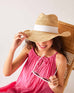 woman in pink dress with seagrove straw hat on with sunglasses in hand
