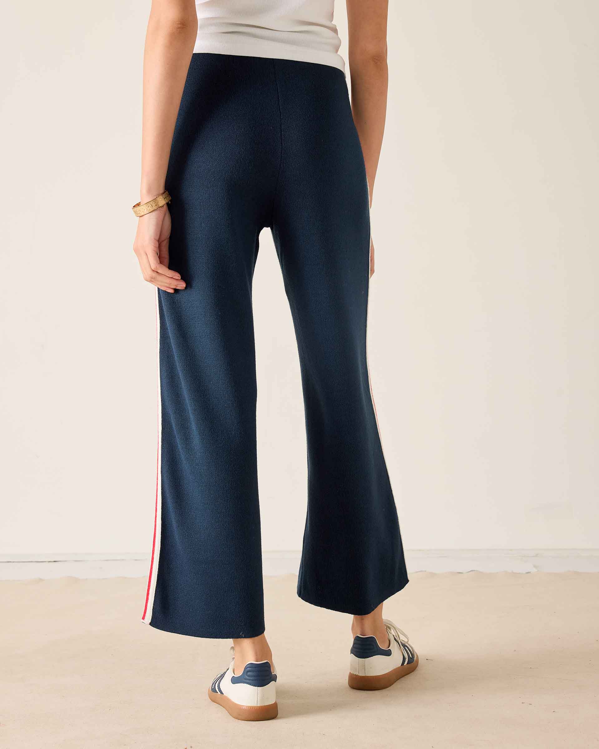 Navy knit wide-leg pants with a red and white stripe detail on the side.