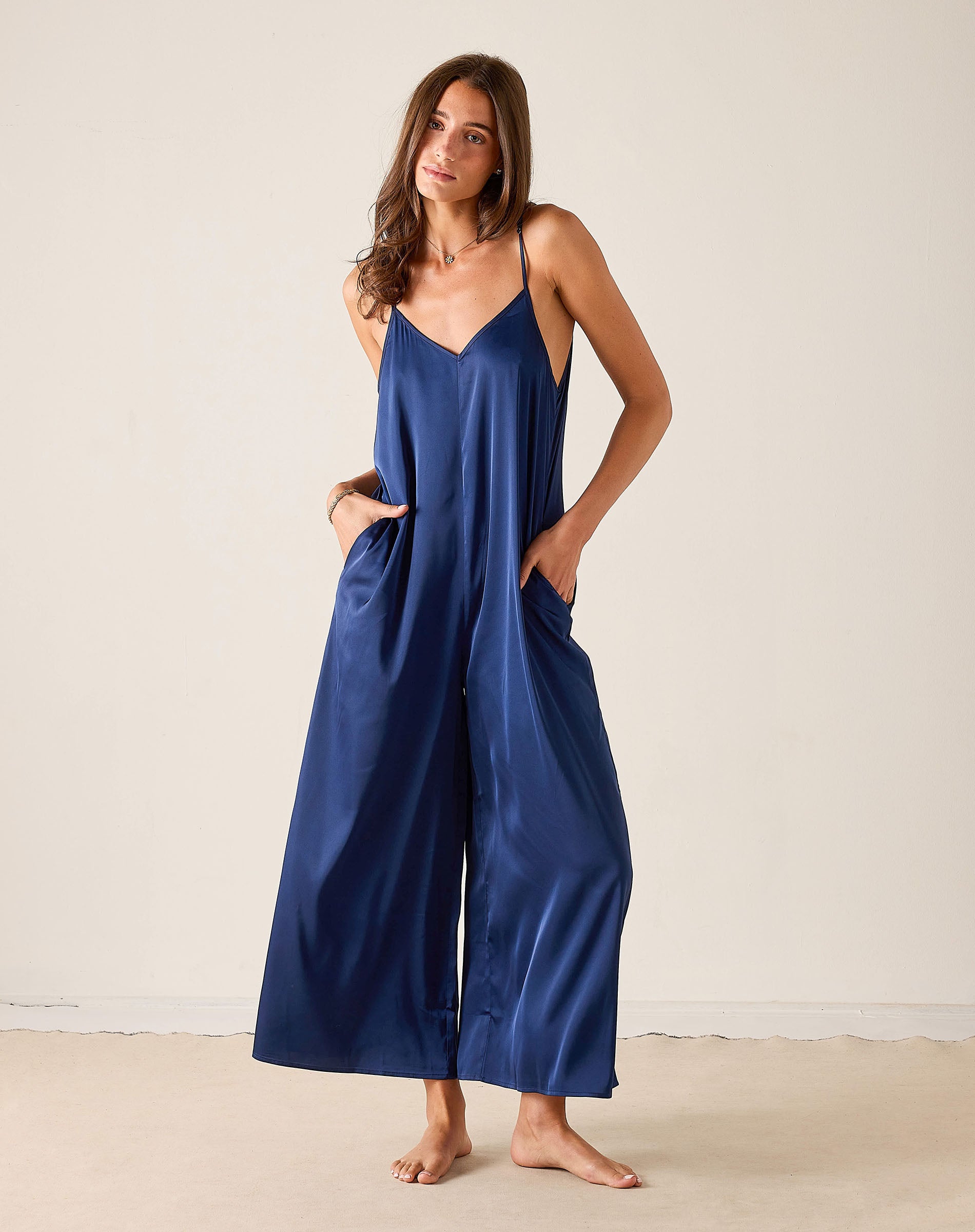 Woman wearing a blue slip dress against a plain background