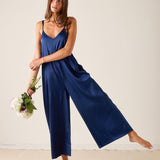 Woman wearing a blue slip dress holding flowers against a plain background