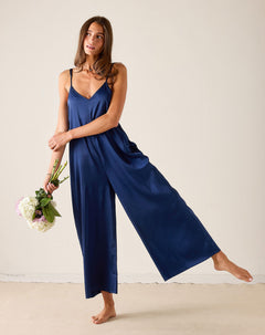 Woman wearing a blue slip dress holding flowers against a plain background