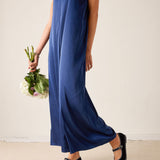 Woman wearing a blue dress holding flowers against a plain background