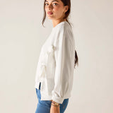 Woman wearing a white blouse and blue jeans against a plain background