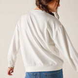 Person wearing a white sweatshirt and blue jeans on a plain background