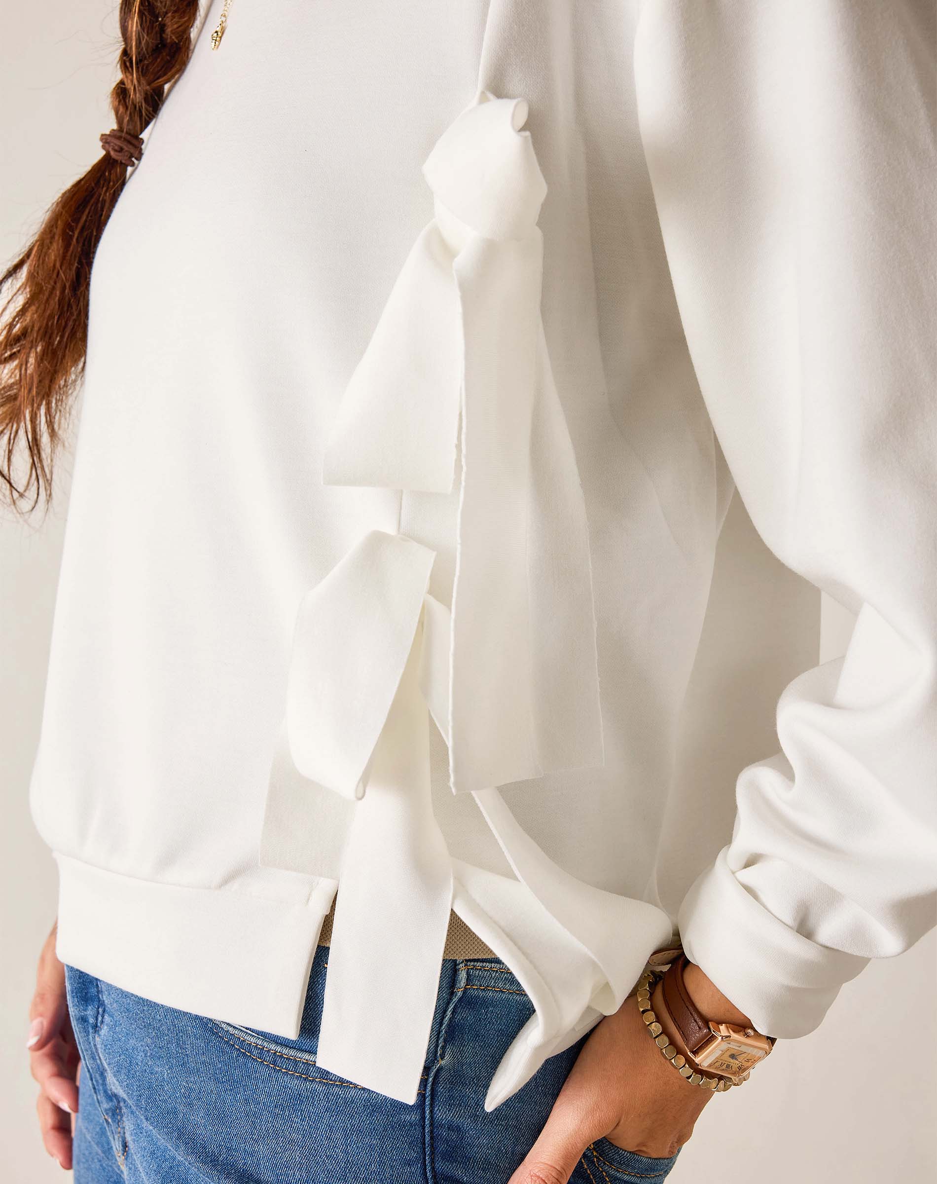 White blouse with ruffled details worn by a person, with a neutral background