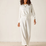 Woman wearing a white outfit against a plain background