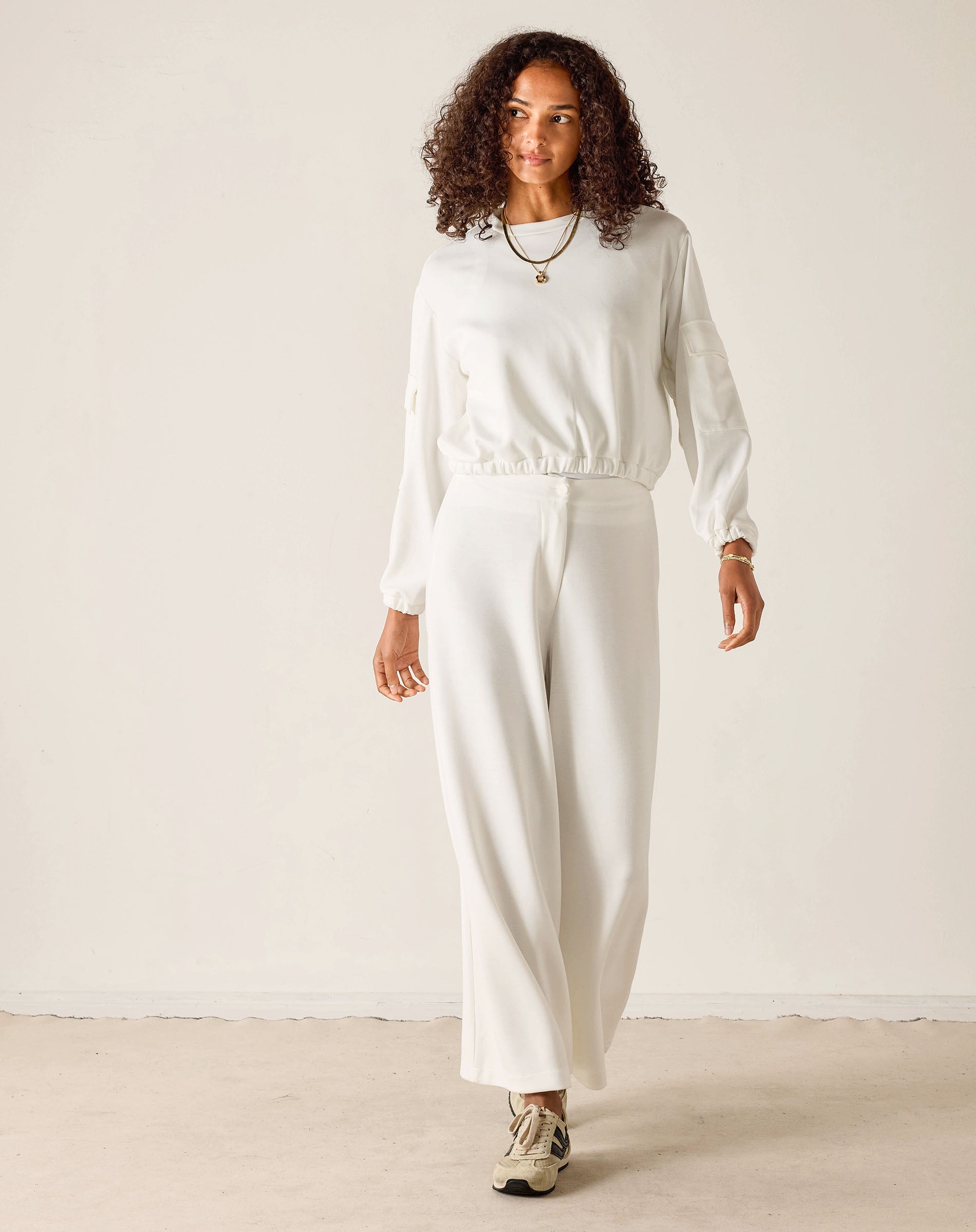 Woman wearing a white outfit against a plain background