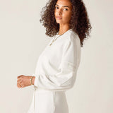 Woman wearing a white outfit against a plain background