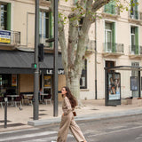 Woman walking on a city street with buildings and trees in the background
