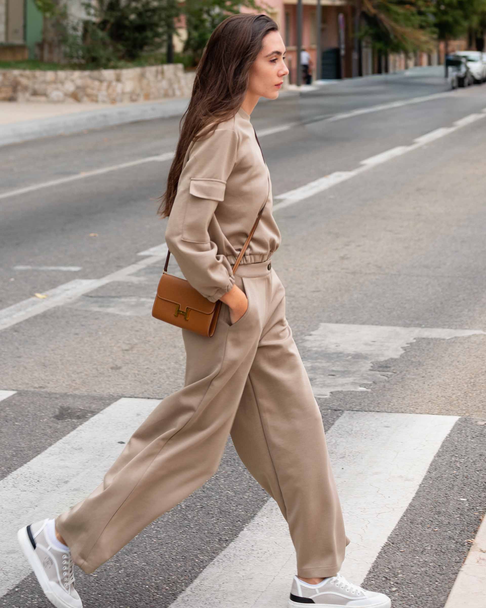Woman in beige outfit crossing a street