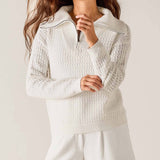 Woman wearing a textured white sweater against a plain background